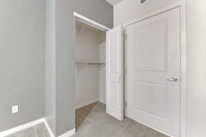 Interior Unit Bedroom, Neutral toned wall paint and carpeting, white doors, folding closet door .