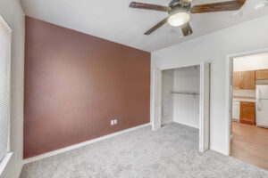 Interior Unit Bedroom, ceiling fan/light fixture, folding closet doors, terracotta toned wall paint on wall right of window.